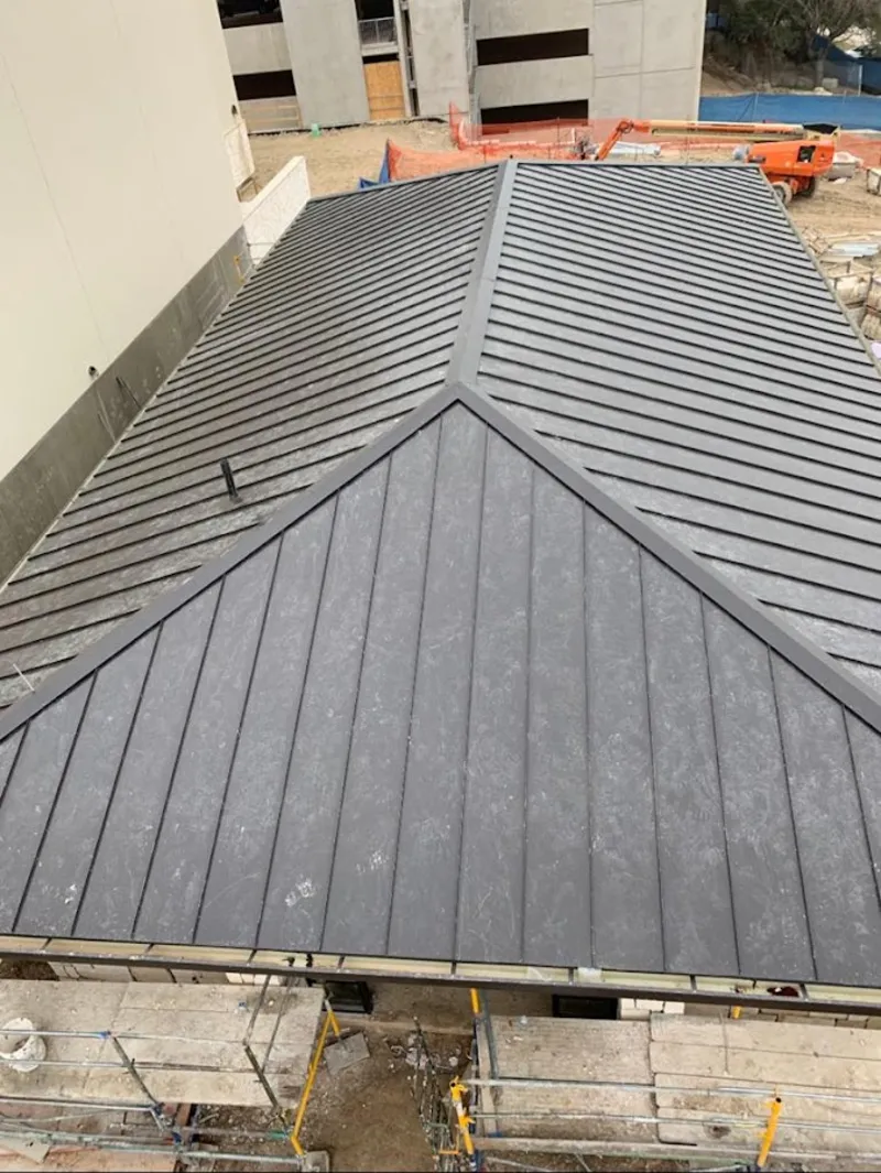 Commercial metal roof construction with crane equipment in Clayton